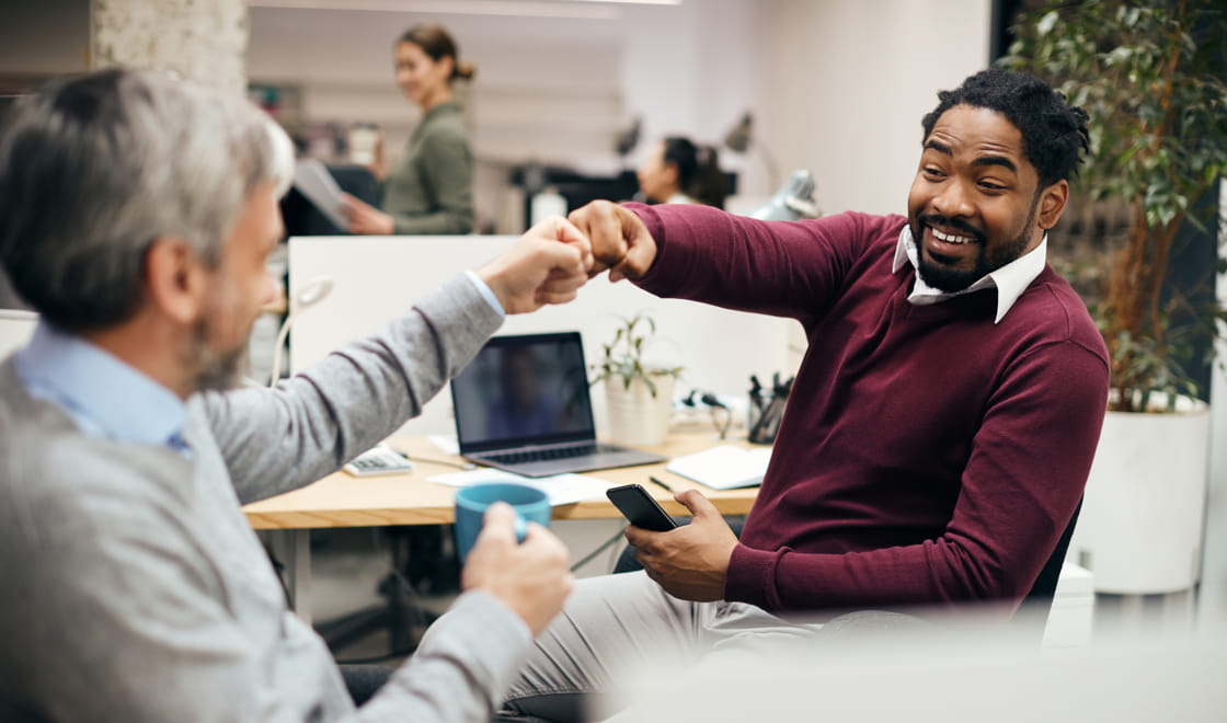 Man, fist bumping a coworker in a contemporary office setting.