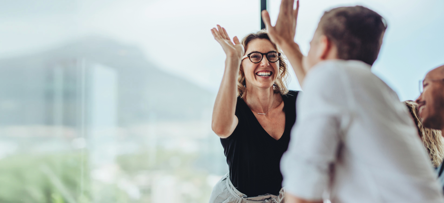 Woman high fiving her coworkers, with a 55 out of 60 scale and a red ‘Encourage the Heart’ leadership behavior banner are in the bottom right corner.
