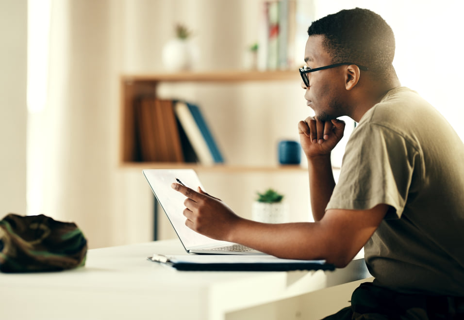 Man, deep in thought while working at a laptop.