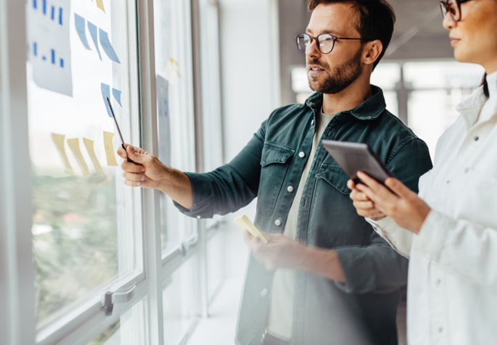Two coworkers reviewing sticky notes.